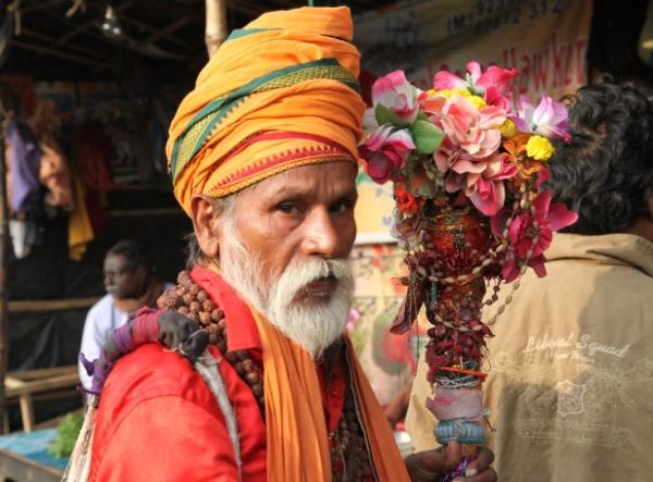 Mann in Bhutan Ein älterer Mann mit vielen Orchideen in der Hand und traditioneller bunter Kleidung, Sikkim Bhutan Rundreise